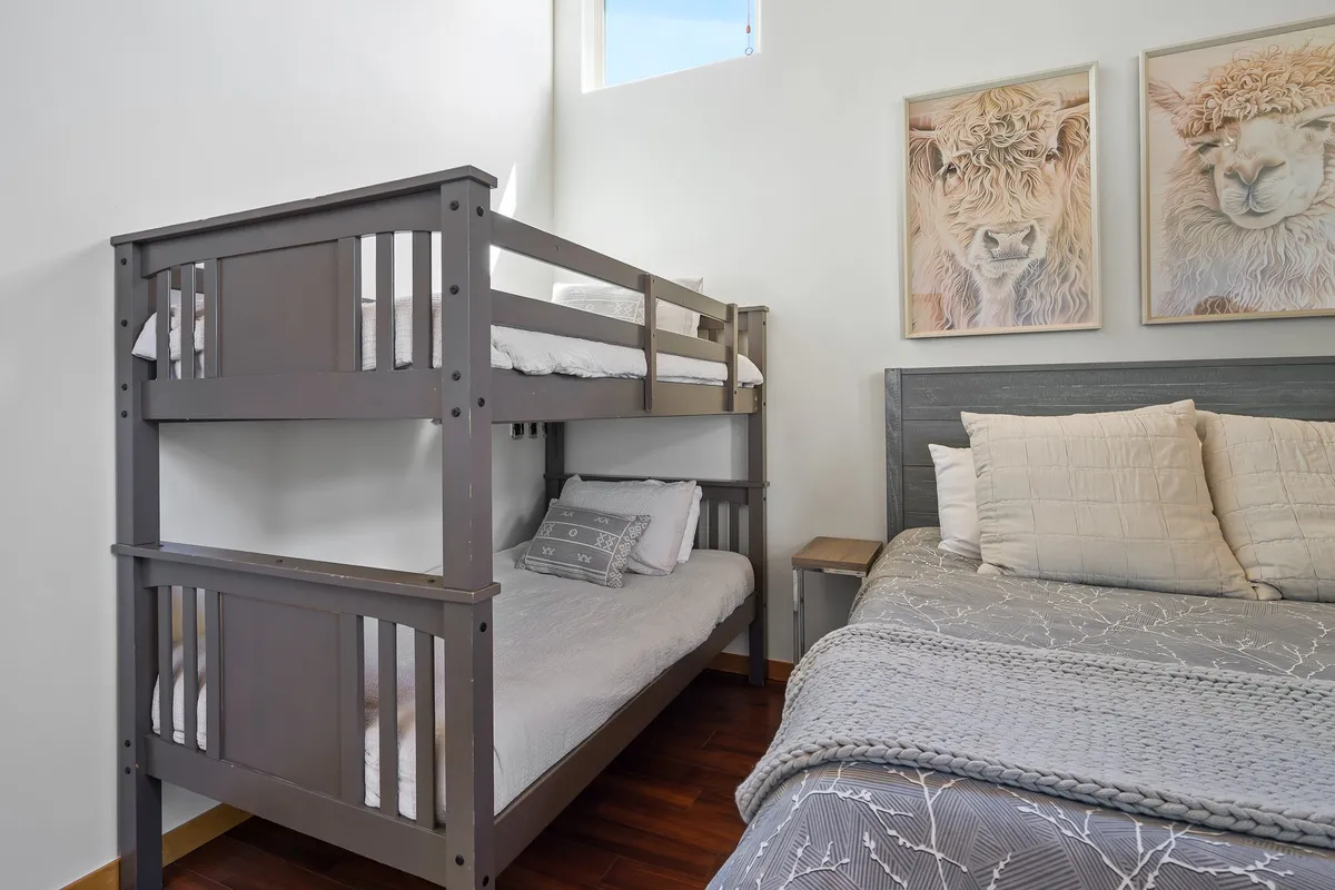 A playful bunk room with a large bunk bed and a comfy large bed, accented by animal artwork. The space is designed for family bonding, sleepovers, and fun evenings, creating a welcoming environment for kids and teens.
